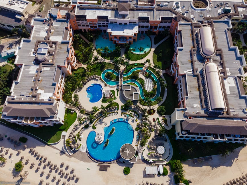 Niebieski basen przy hotelu all-inclusive otoczony palmami na tle morza