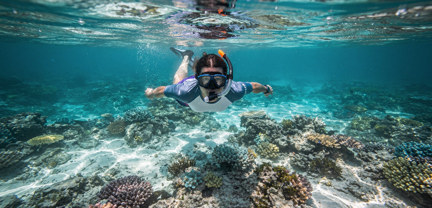 Snorkeler unoszący się nad płytką rafą koralową w krystalicznie czystej wodzie Zatoki Świń na Kubie